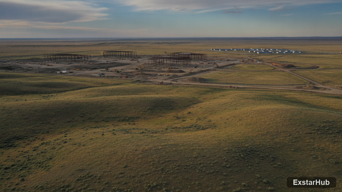 Data center construction in Wyoming with a distant 'man camp' visible on the horizon.