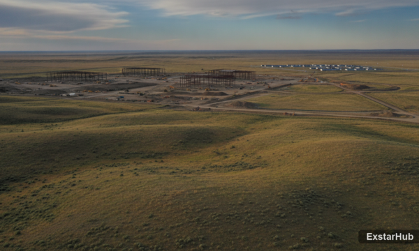 Data center construction in Wyoming with a distant 'man camp' visible on the horizon.